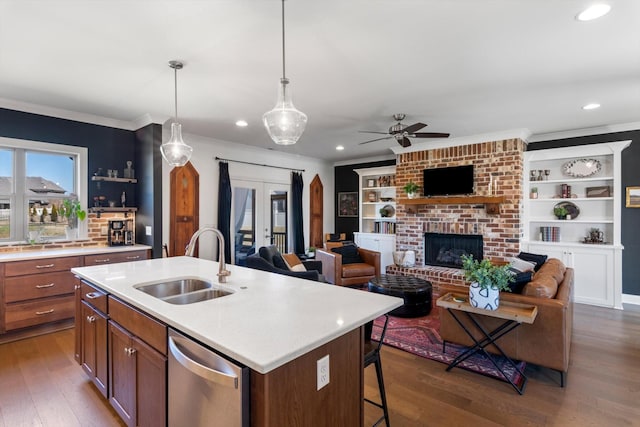 kitchen with dark wood-style flooring, ornamental molding, a sink, stainless steel dishwasher, and a brick fireplace