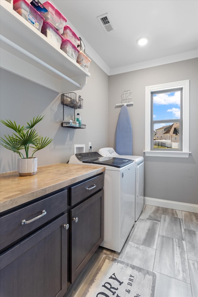 clothes washing area featuring visible vents, washer and dryer, cabinet space, crown molding, and baseboards