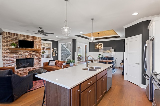 kitchen with a brick fireplace, light wood-style flooring, open floor plan, and a sink