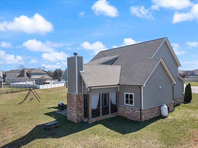 back of property with brick siding, a chimney, a lawn, and a shingled roof