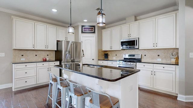 kitchen featuring dark wood-type flooring, a center island with sink, a sink, appliances with stainless steel finishes, and white cabinets