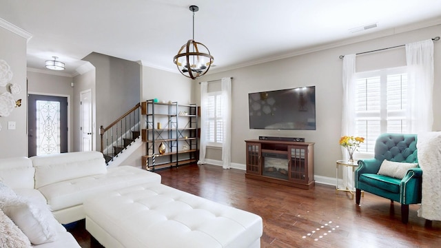 living area with visible vents, wood finished floors, an inviting chandelier, crown molding, and stairs