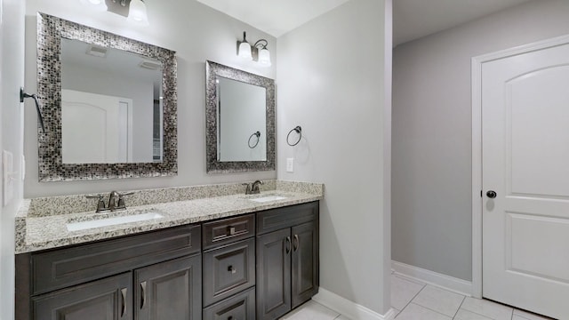 bathroom with tile patterned floors, double vanity, baseboards, and a sink