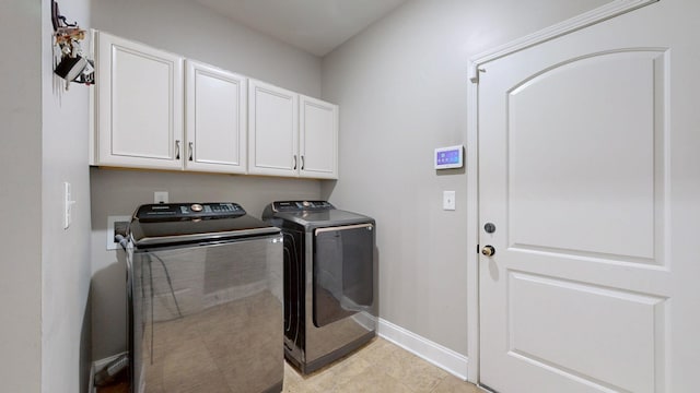 clothes washing area featuring cabinet space, baseboards, and washer and clothes dryer