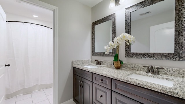 bathroom featuring tile patterned floors, double vanity, visible vents, and a sink