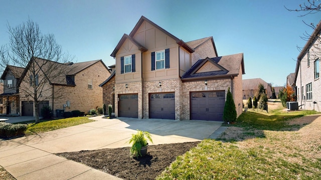 view of front of property with brick siding, a front lawn, concrete driveway, central AC, and a garage