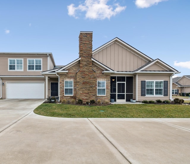 view of front facade with a front yard, a chimney, concrete driveway, a garage, and board and batten siding