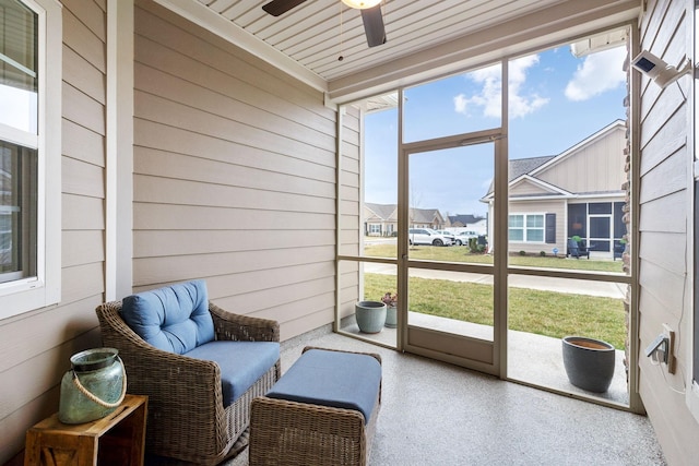 sunroom / solarium with a residential view and ceiling fan