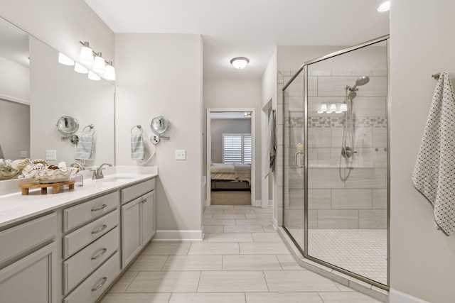 ensuite bathroom with tile patterned flooring, connected bathroom, a shower stall, baseboards, and vanity