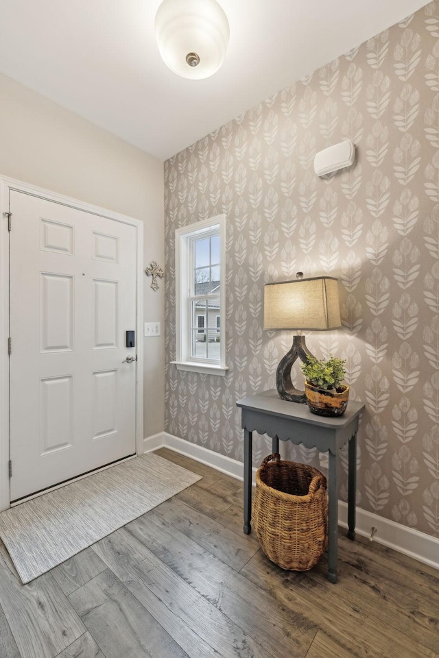 entryway with wallpapered walls, wood finished floors, and baseboards