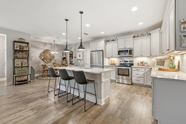 kitchen with a breakfast bar, tasteful backsplash, light wood finished floors, and stainless steel appliances