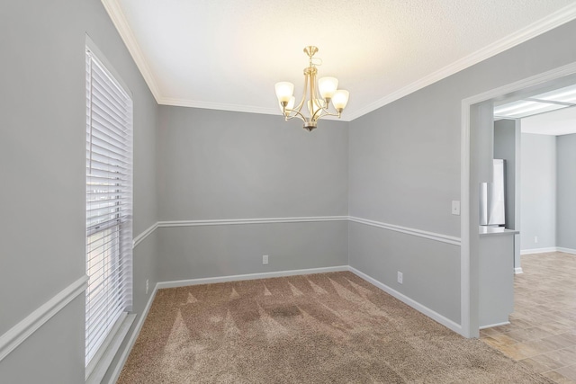 carpeted empty room featuring an inviting chandelier, baseboards, and ornamental molding