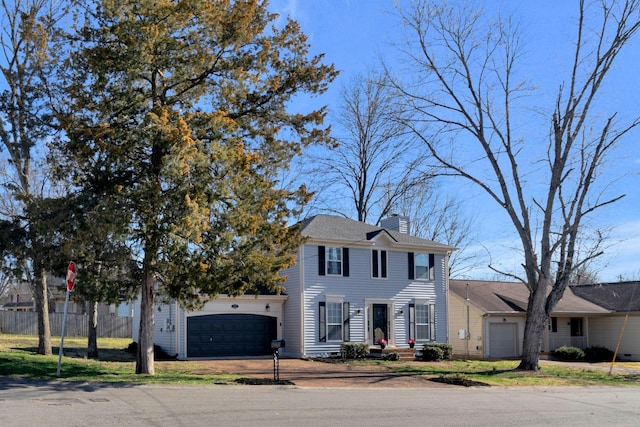 view of front of property featuring driveway, a chimney, and a garage