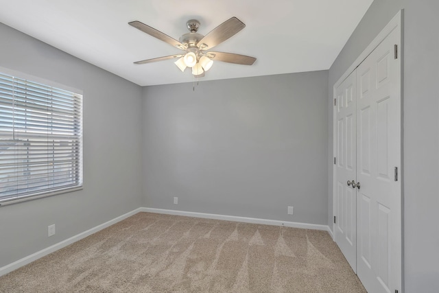 unfurnished bedroom with a closet, baseboards, a ceiling fan, and carpet flooring