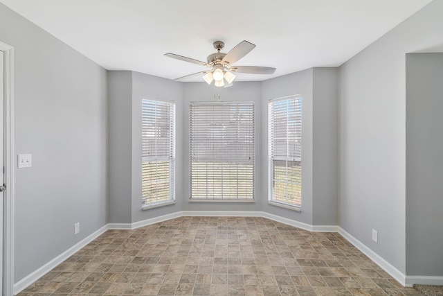 empty room with baseboards, a healthy amount of sunlight, and ceiling fan