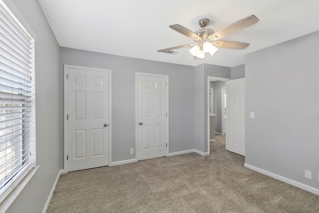 unfurnished bedroom featuring carpet flooring, visible vents, baseboards, and ceiling fan