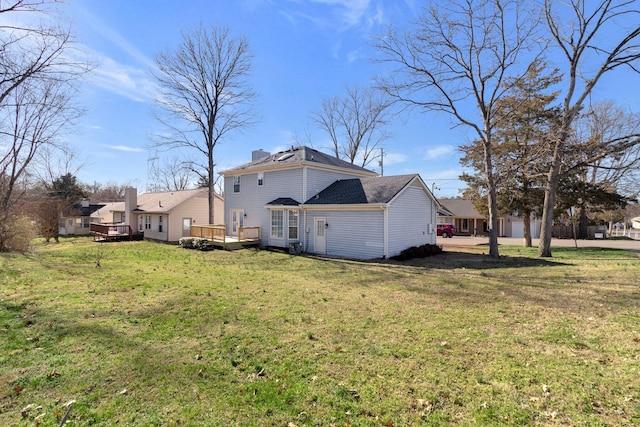 back of house featuring a yard, a chimney, and a wooden deck