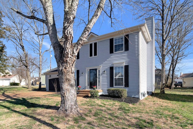 colonial-style house featuring a front lawn, an attached garage, and a chimney