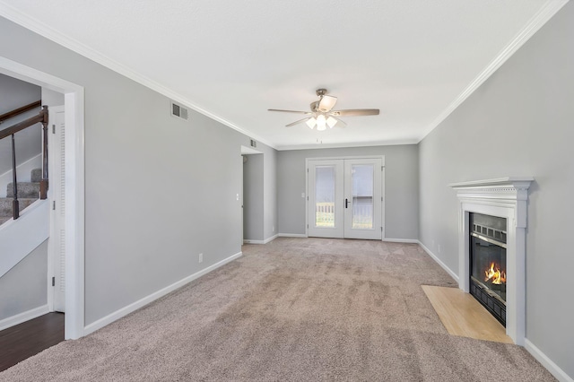 unfurnished living room with baseboards, a fireplace with flush hearth, french doors, crown molding, and carpet flooring