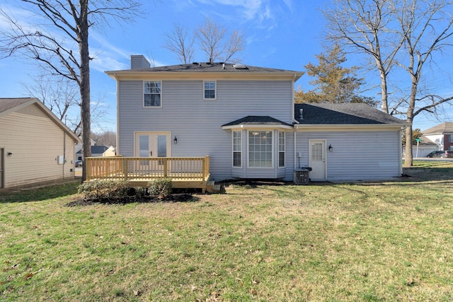 back of property with a yard, a chimney, and a deck