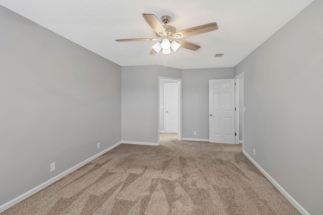 empty room featuring baseboards, visible vents, carpet floors, and ceiling fan