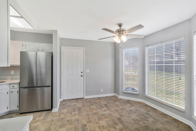 kitchen with white cabinetry, freestanding refrigerator, light countertops, baseboards, and ceiling fan