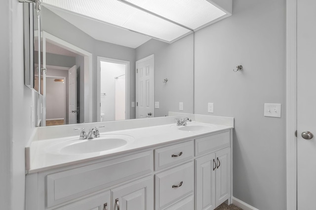 bathroom featuring double vanity, baseboards, and a sink