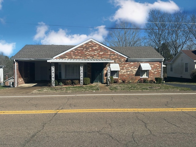 view of front of home featuring brick siding, driveway, and a shingled roof