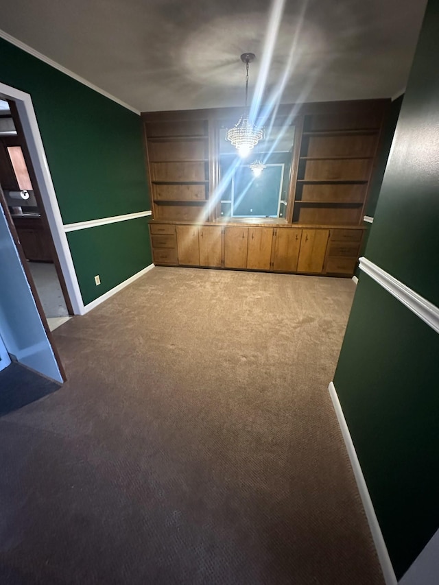 below grade area with baseboards, a chandelier, carpet flooring, and crown molding