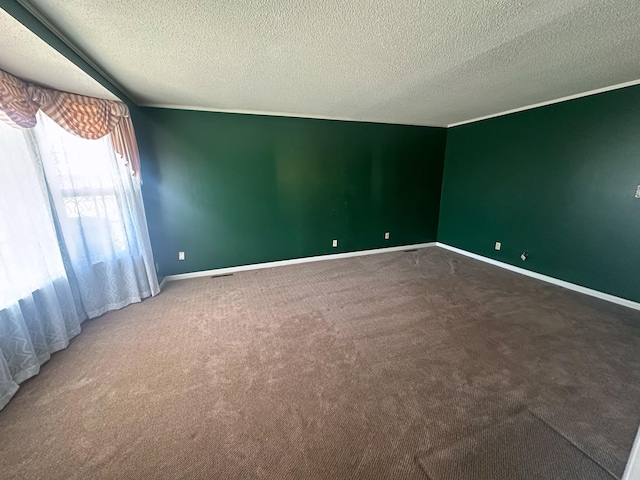 unfurnished room with carpet flooring, visible vents, baseboards, and a textured ceiling