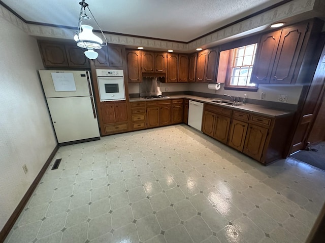 kitchen with visible vents, a sink, dark countertops, white appliances, and crown molding