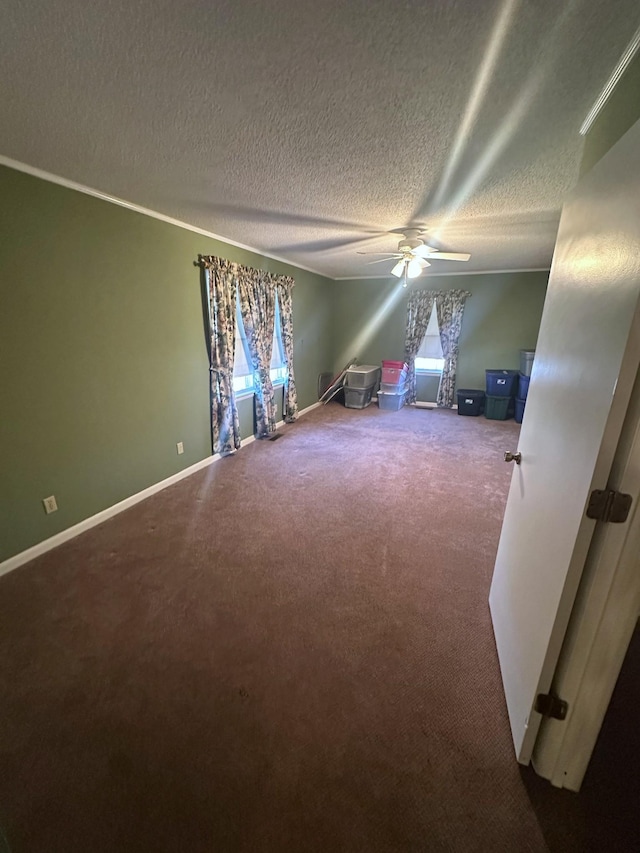 unfurnished bedroom with a textured ceiling, carpet flooring, crown molding, baseboards, and ceiling fan