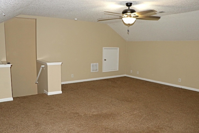 additional living space featuring visible vents, lofted ceiling, carpet floors, a textured ceiling, and a ceiling fan