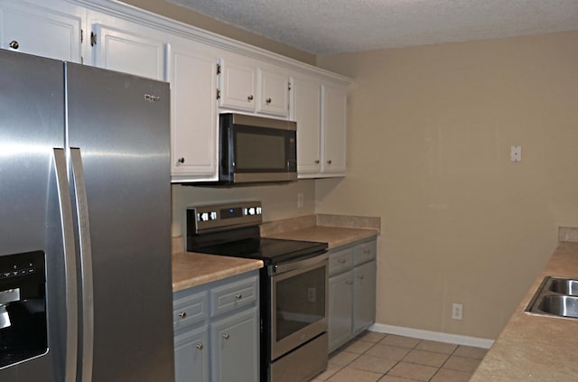 kitchen with light tile patterned floors, appliances with stainless steel finishes, white cabinetry, and light countertops