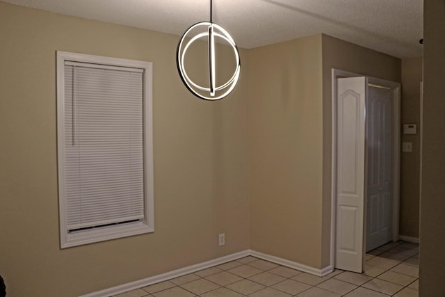 unfurnished dining area featuring light tile patterned floors, baseboards, and a textured ceiling