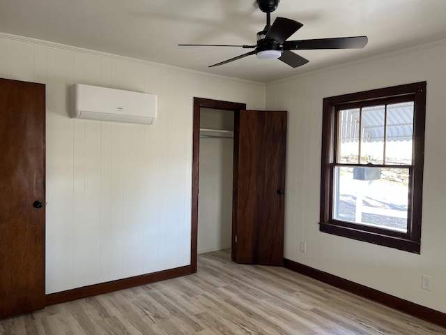 unfurnished bedroom featuring crown molding, wood finished floors, baseboards, and a wall mounted AC