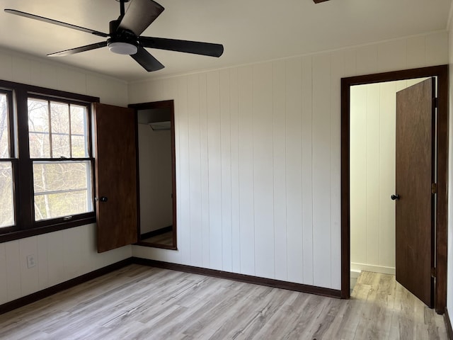 unfurnished bedroom with multiple windows, baseboards, and light wood-style floors