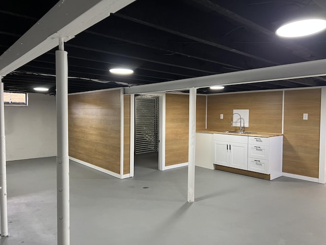 finished basement featuring wood walls and a sink