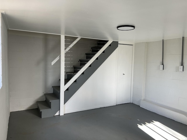 basement with stairs and concrete block wall