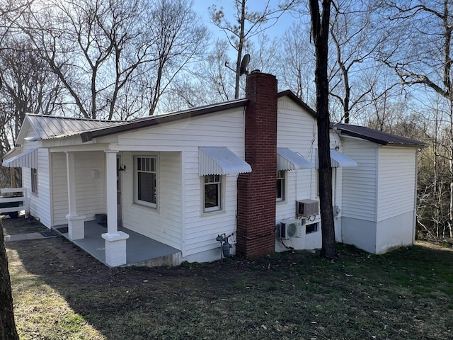 rear view of house featuring metal roof and a chimney