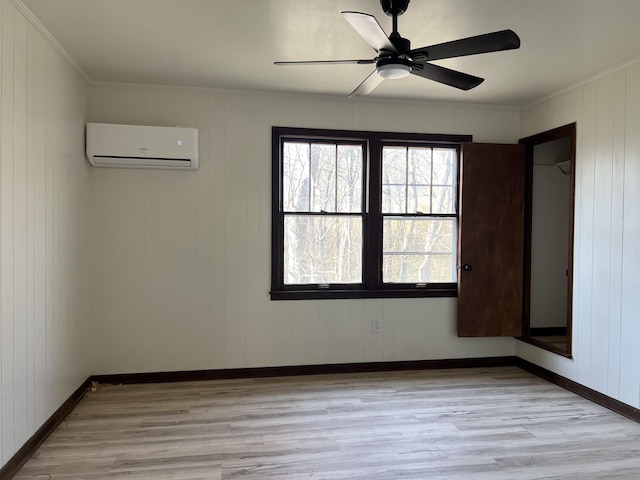 unfurnished room featuring baseboards, a wall mounted air conditioner, crown molding, and light wood-style floors