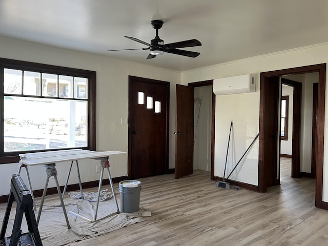 entryway with crown molding, baseboards, an AC wall unit, light wood-style floors, and a ceiling fan