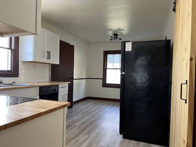 kitchen featuring light wood-type flooring, black appliances, tasteful backsplash, white cabinets, and butcher block counters