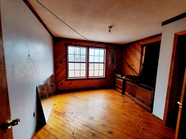 interior space featuring wooden walls, light wood finished floors, and electric panel