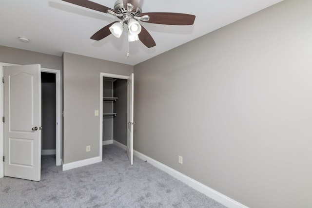 unfurnished bedroom with a ceiling fan, a closet, baseboards, light colored carpet, and a spacious closet