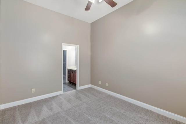 carpeted empty room with ceiling fan, baseboards, and vaulted ceiling