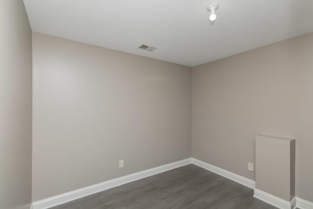 spare room featuring visible vents, baseboards, and dark wood finished floors