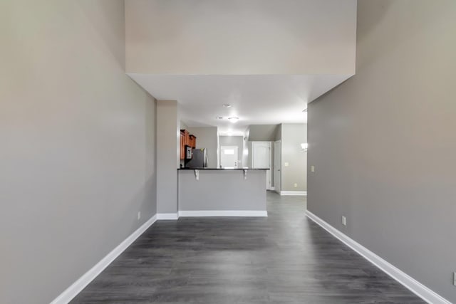 unfurnished living room featuring baseboards and dark wood-type flooring