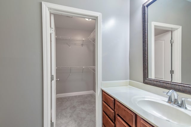 bathroom featuring a walk in closet, vanity, and baseboards