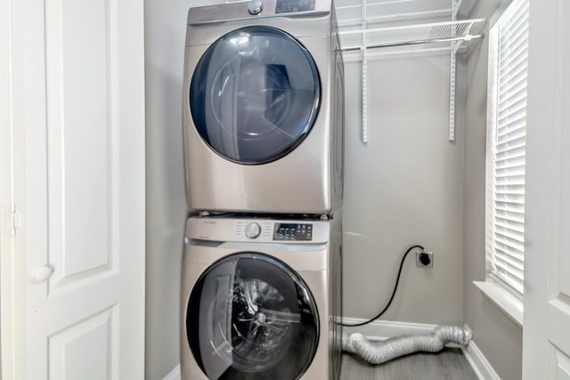 laundry room with baseboards and stacked washer and clothes dryer